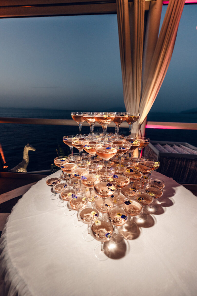 A champagne coupe tower on a round table at dusk, the sea behind it, Weddings Amalfi