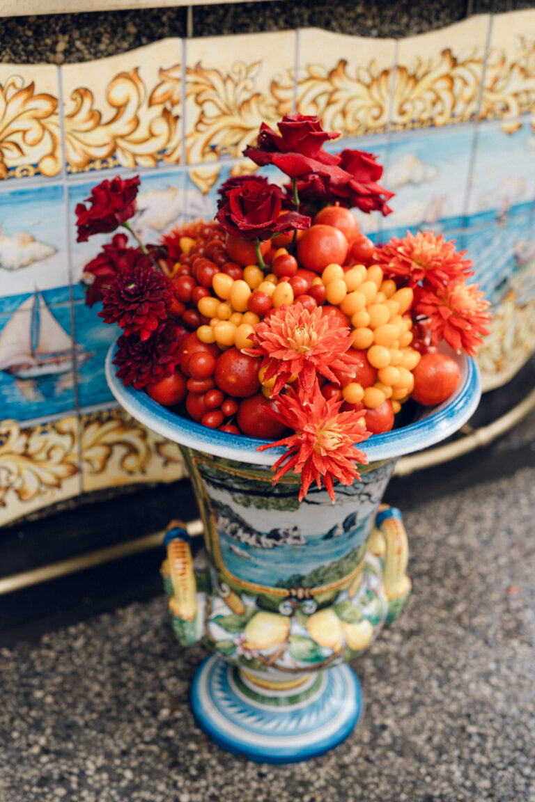 A painted ceramic urn of red dahlias, cherry tomatoes and kumquats in front of tiled panels, Weddings Amalfi