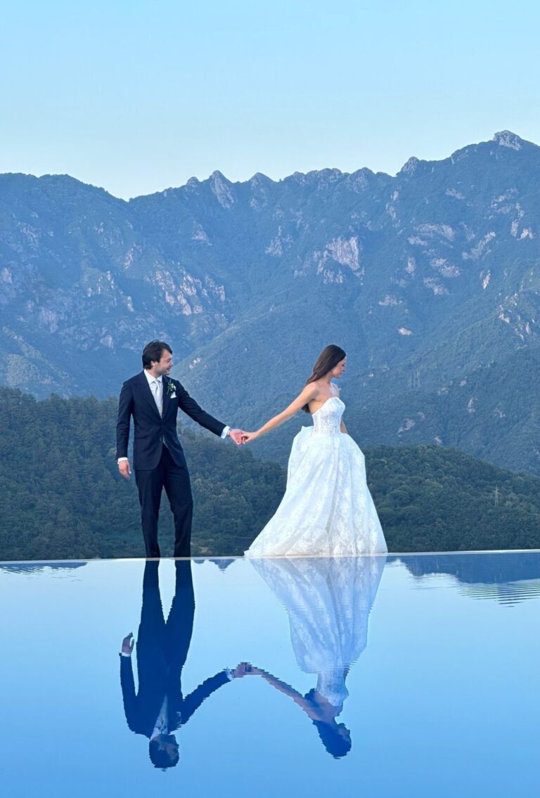 The couple on the edge of an infinity pool, reflected in the water, with the mountains behind Ravello, Weddings Amalfi