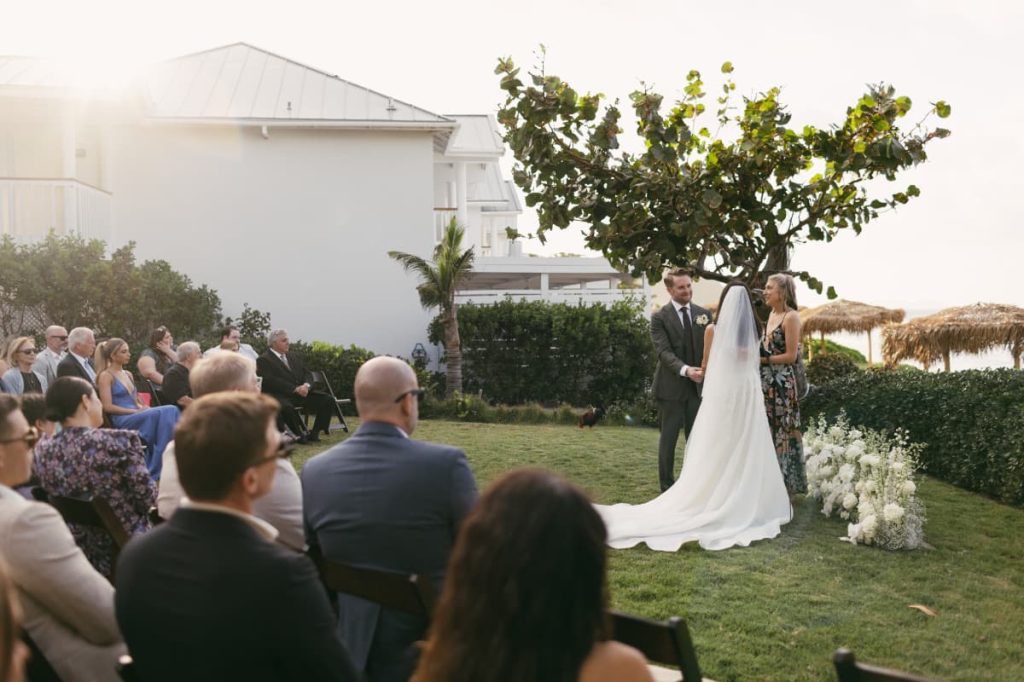 A ceremony on the lawn with guests seated facing the couple, beside the resort building