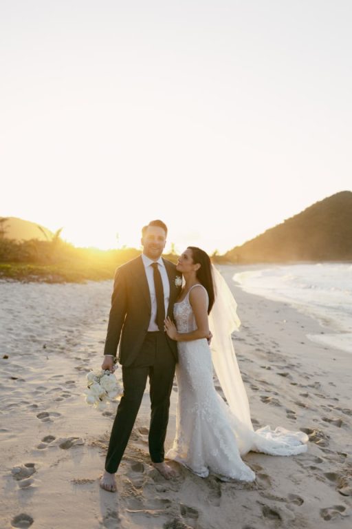 A bride and groom embracing on the beach at golden hour