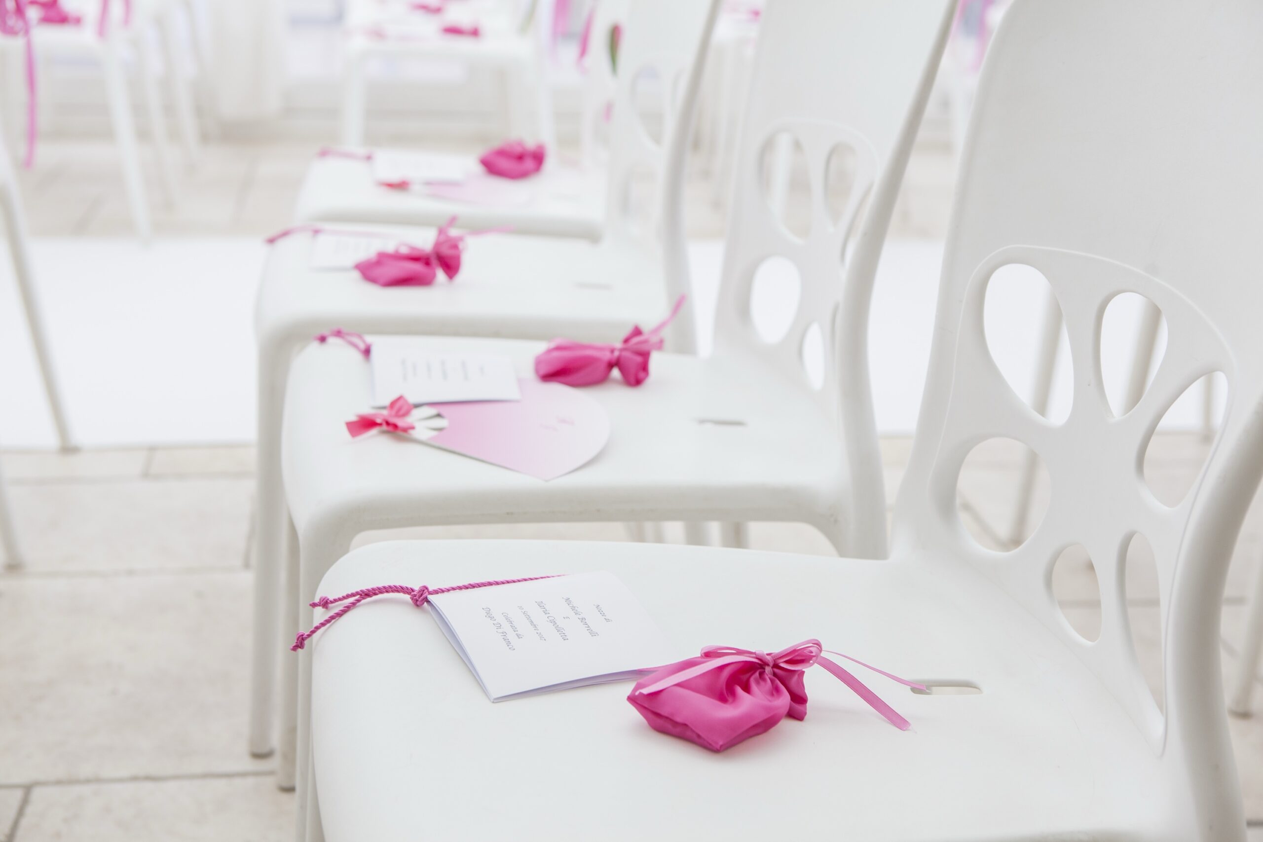 Order-of-service cards and pink satin favours left on each ceremony chair, WEM Eventi