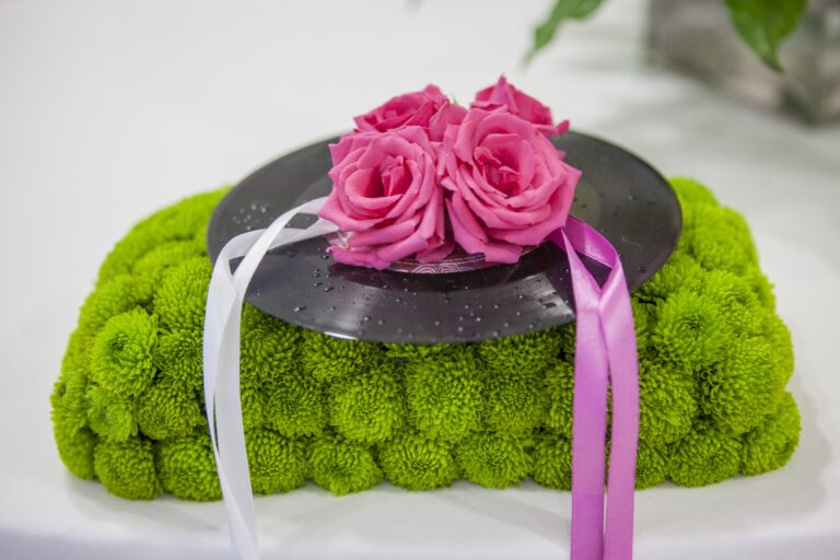 A ring cushion made from a vinyl record and pink roses on a bed of green chrysanthemums, from a rock-themed wedding, WEM Eventi