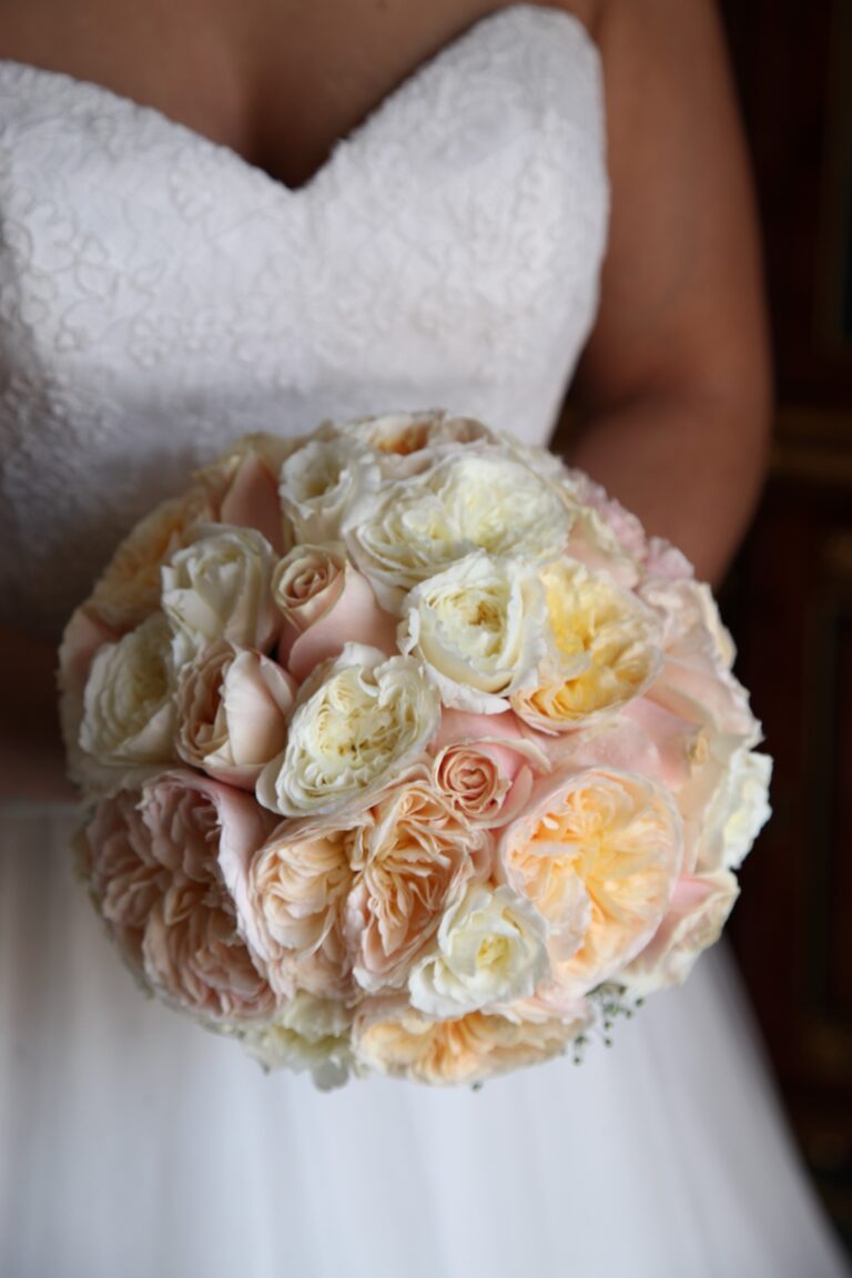 The bride holding a round bouquet of peach and cream garden roses, WEM Eventi