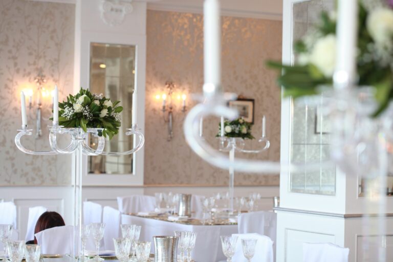 Crystal candelabra with white roses over round tables in a panelled reception room, WEM Eventi