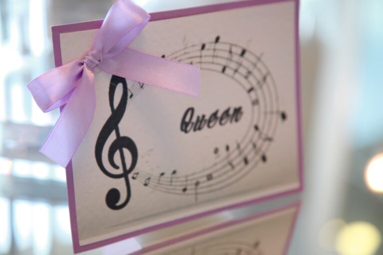 A table name card printed with a treble clef and stave, tied with a lilac bow, WEM Eventi
