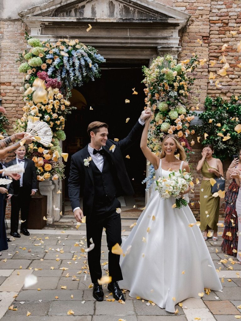 A couple leave a Venetian church under thrown petals, Whitesfilm Wedding Videography