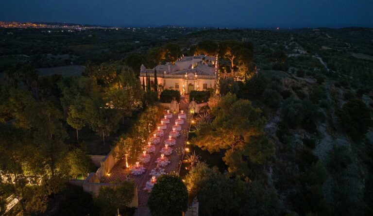 Aerial view at night of a long candlelit dinner in the gardens of a Sicilian estate, Whitesfilm Wedding Videography