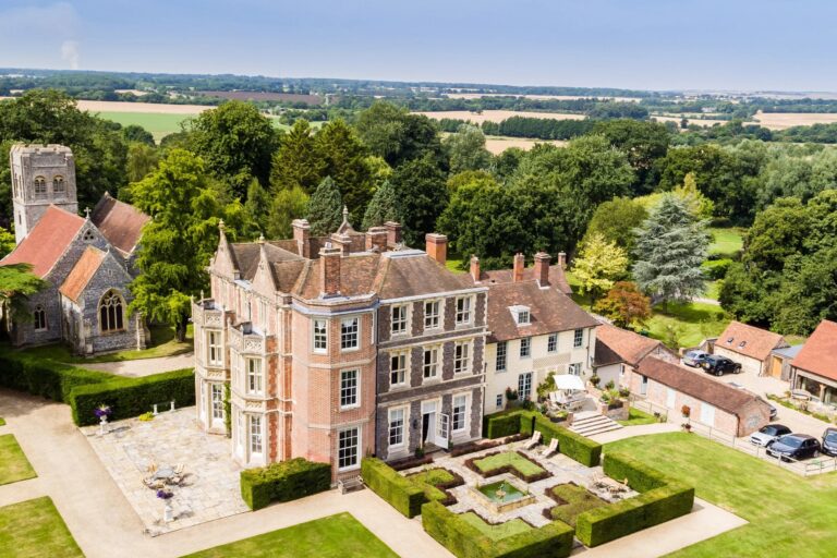 Aerial view of the Victorian Gothic front of Wickham House with St Swithun's church beside it, the box parterre and the downs beyond, Wickham House