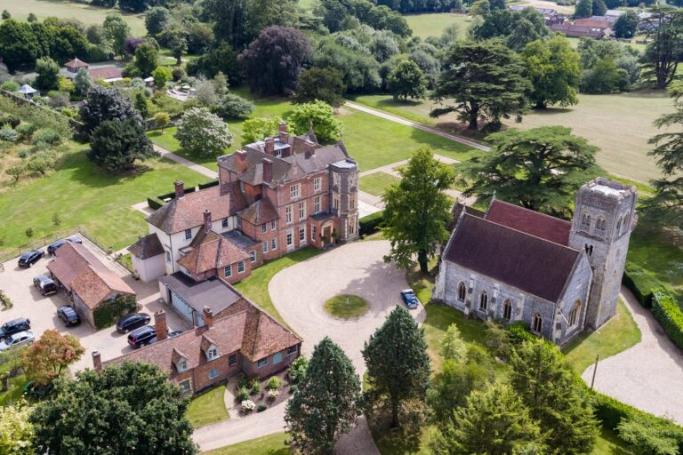 Aerial view of the house, the church and the stable courtyard, with cedars and parkland around them, Wickham House