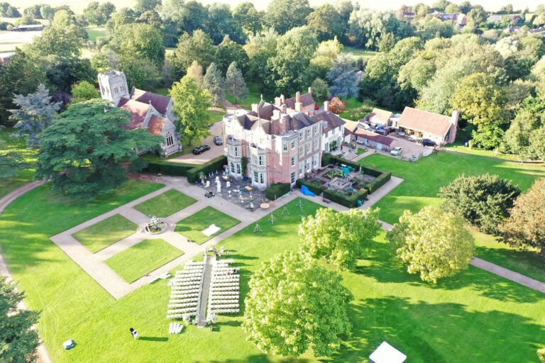 An outdoor ceremony laid out on the lawn below the house, with white chairs either side of an aisle, Wickham House