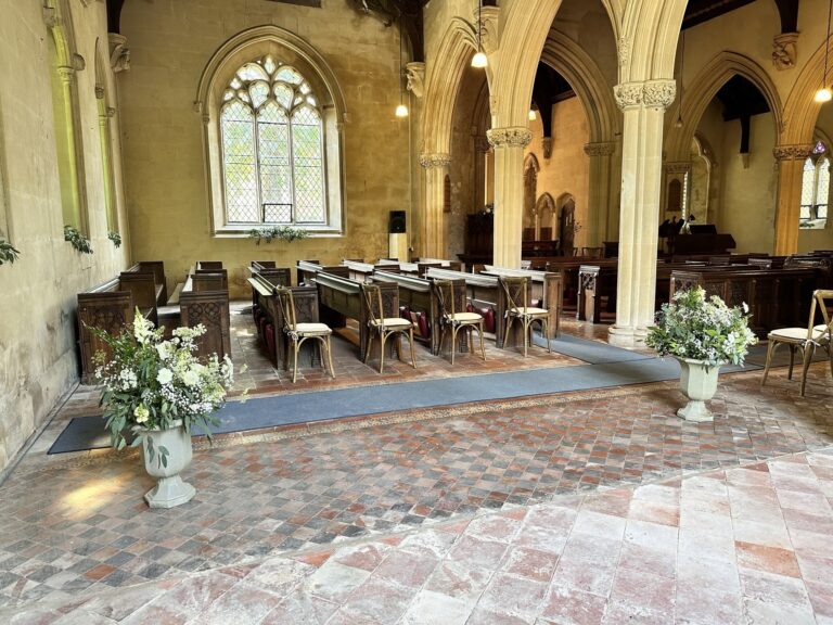 The church floor of old clay tiles, with chairs and urns of white flowers set out for a service, Wickham House