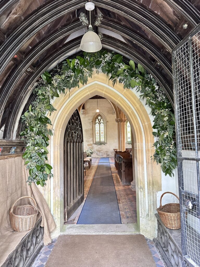 The church porch framed with a garland of greenery and white flowers, Wickham House
