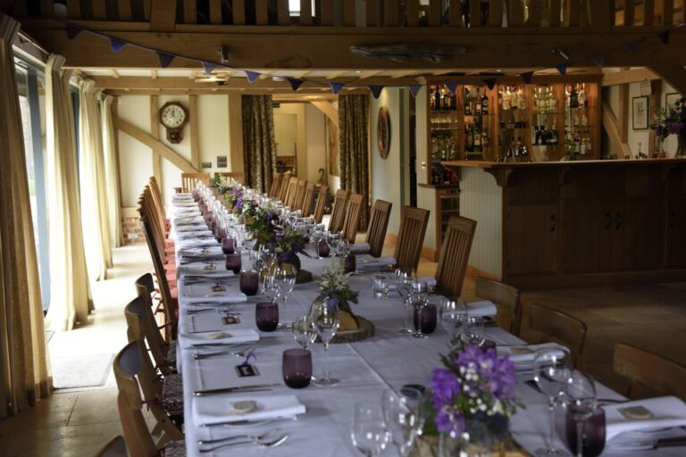 The Barn laid with a single long table in white linen and bunting overhead, Wickham House