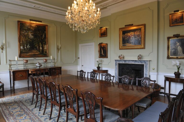 The dining room in the main house by day, with its chandelier, paintings and mahogany table, Wickham House