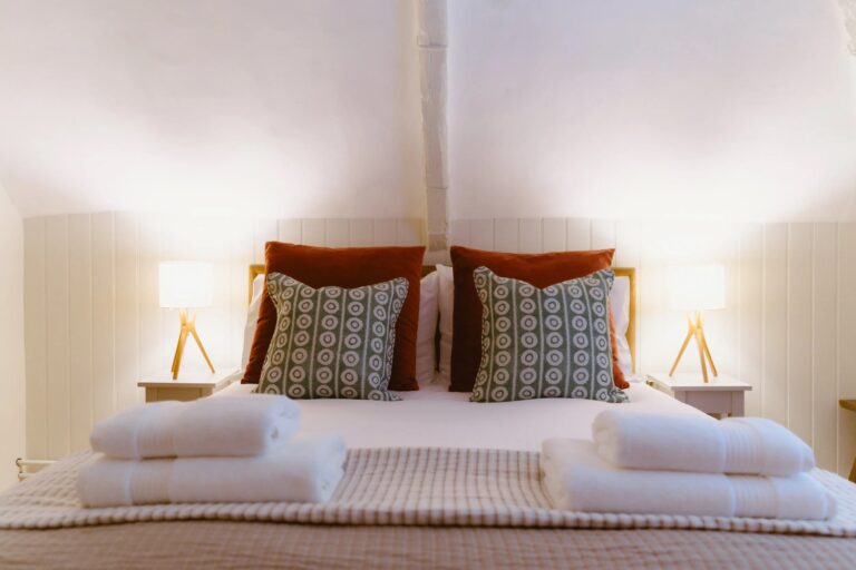 A double bedroom at Swann Cottage with panelled walls, tripod lamps and patterned cushions, Worstead Estate