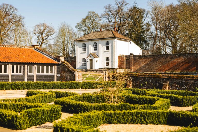 The courtyard knot garden with the tiled range of The Woodyard and the white Estate Cottage beyond the wall, Worstead Estate