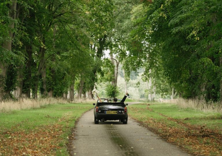 A tree-lined drive through Worstead Park in early autumn, with an open-top car heading away, Worstead Estate
