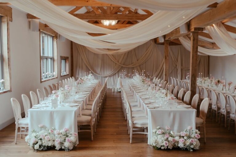 The Mulberry Room laid with long tables, cane-back chairs and pink and white flowers under draped ceiling fabric, Worstead Estate