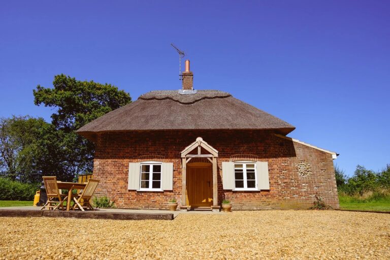 New Lane Cottage, a thatched brick cottage with a timber porch and a gravel drive, Worstead Estate