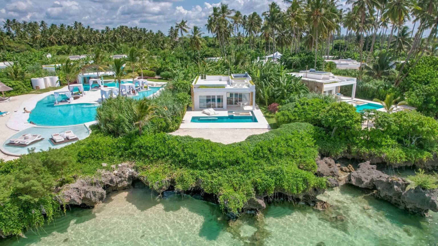 An aerial view of villas and pools among the tropical gardens