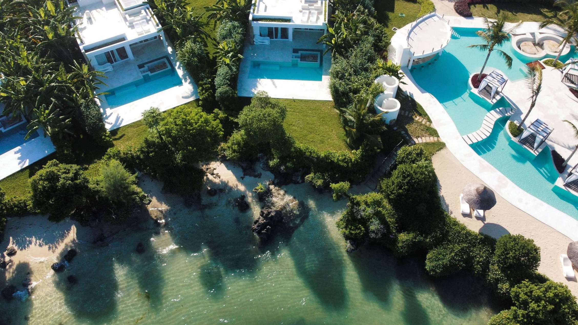 Aerial view of villa rooftops, the lagoon-style pool and rocky shoreline, Ycona Luxury Resort