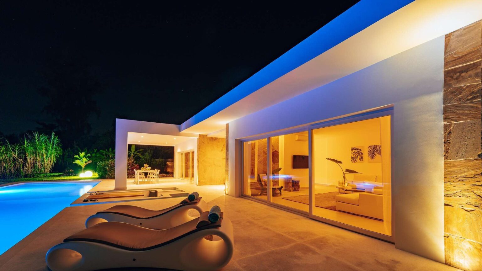 A pool villa at night with the pool and terrace lit
