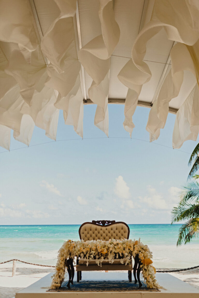 A carved, gilded chair set on the sand beneath a paper canopy, YD Events