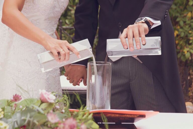 A couple pouring sand into a glass during a unity ceremony, YD Events