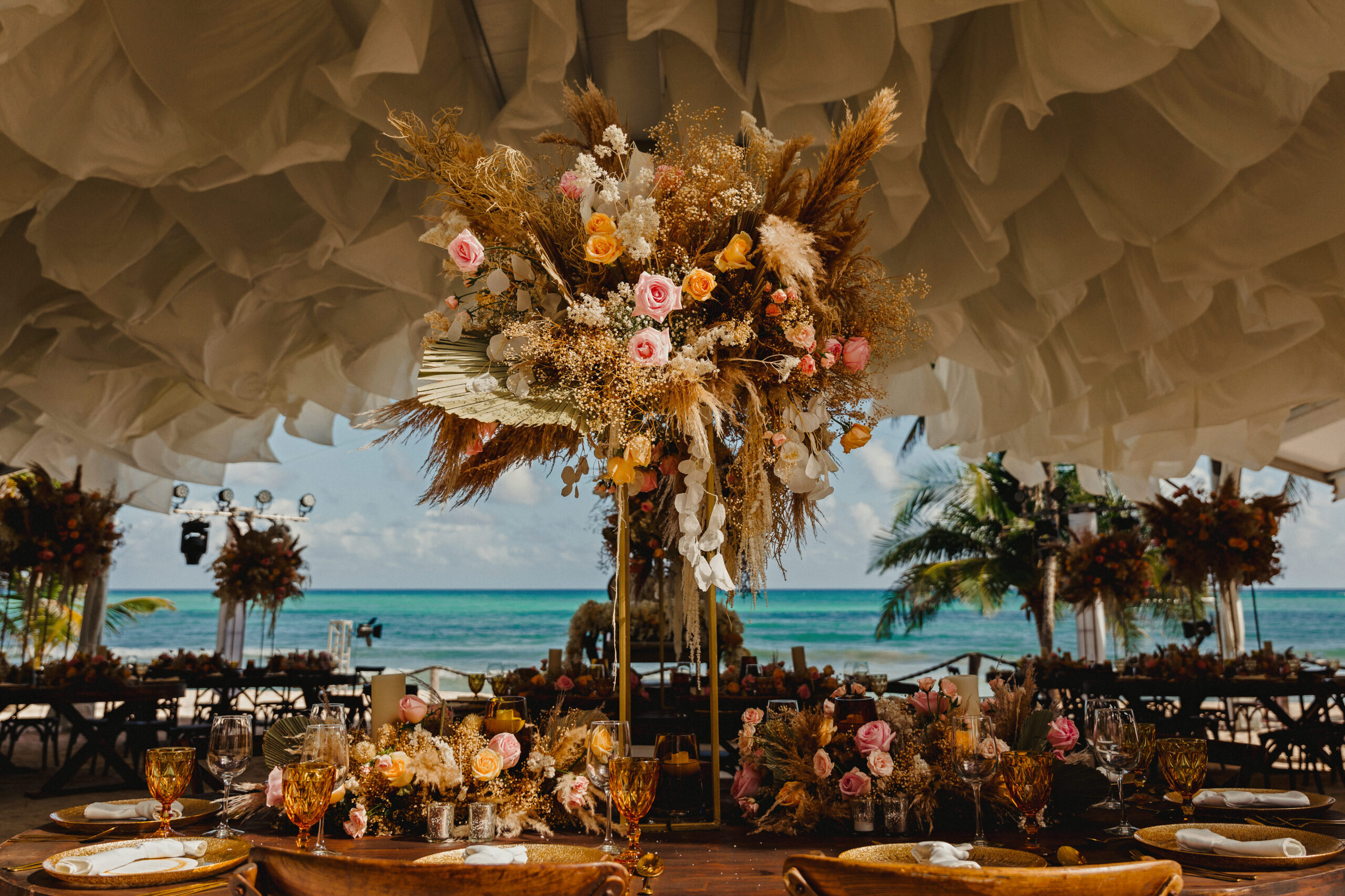 A reception table under a hanging paper canopy with dried-flower centrepiece, looking out to the Caribbean, YD Events