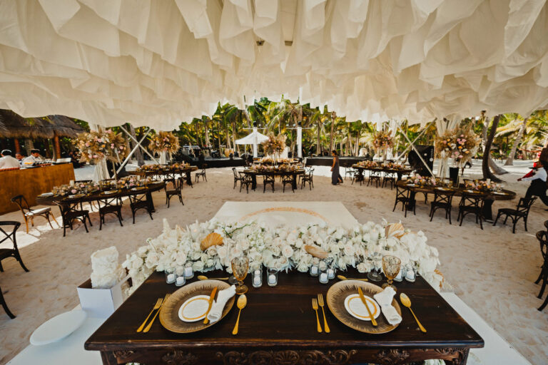 The couple's table with white florals and gold place settings under a paper canopy, with guest tables beyond, YD Events