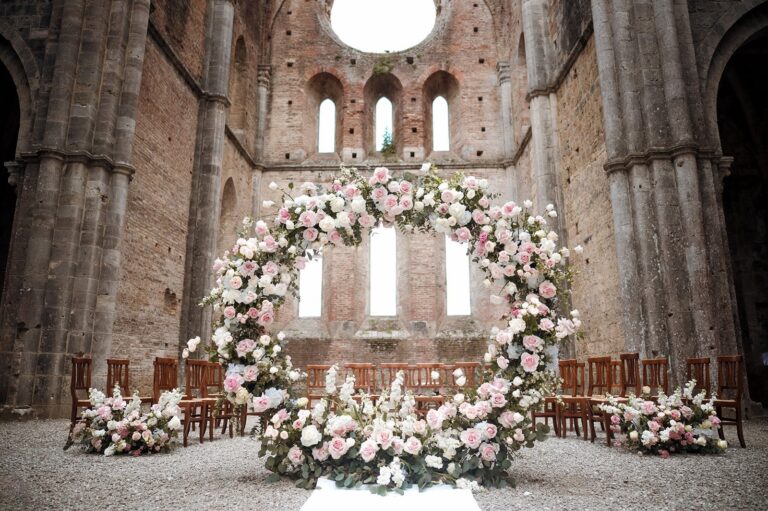 A circular arch of pink and white roses inside the roofless nave of San Galgano Abbey, Siena, Your Secret Tuscany
