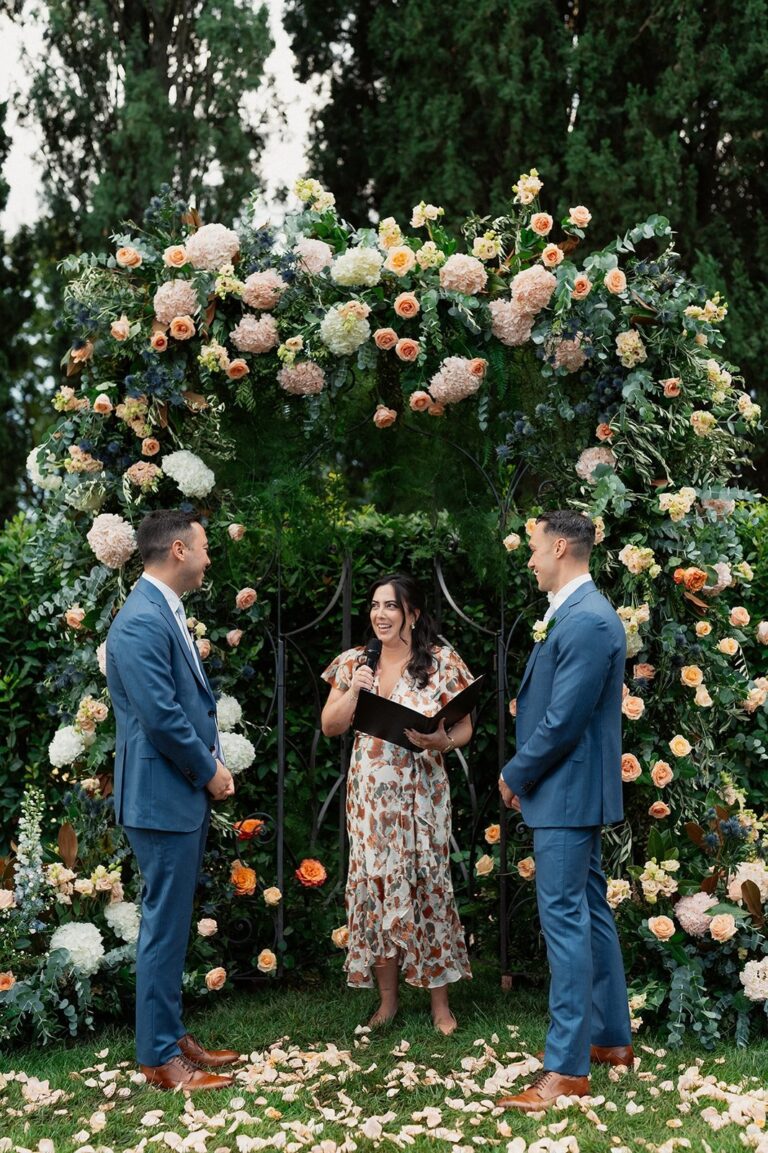 A ceremony under a rose and thistle arch in a Tuscan garden, guests laughing, confetti on the grass, Your Secret Tuscany