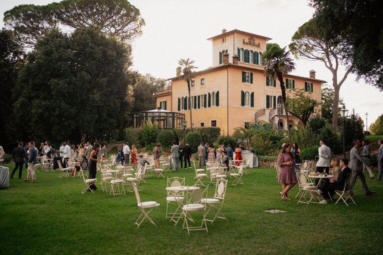 Guests on the lawn at golden hour in front of a tiered Tuscan villa and its stone staircase, Your Secret Tuscany