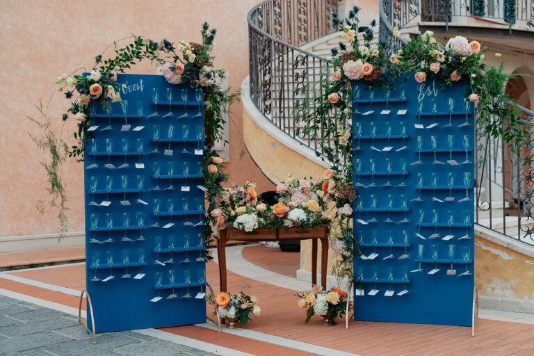 A blue champagne wall dressed with peach florals beside an antique escort-card table, Your Secret Tuscany